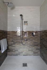 纽伯里卡尔纳翁阿姆斯酒店的浴室铺有棕色瓷砖,设有淋浴。