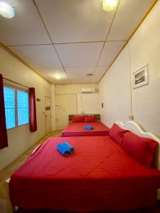 华欣Plaza Huahin的宿舍间的两张床,配有红色床单和枕头