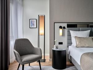华沙华沙莱昂纳多皇家酒店的一间卧室配有一张床、一把椅子和一盏灯