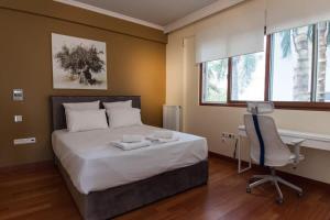 雅典Riviera Retreat 3 Bedroom Voula Luxury Haven Apt的一间卧室配有一张床、一张桌子和一把椅子
