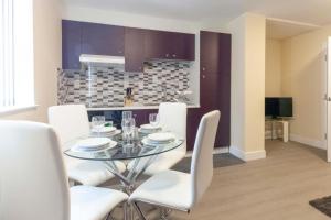 拉夫堡SAV Apartments Clarence Street-Loughborough的一间设有玻璃桌和白色椅子的用餐室