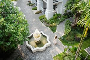 清迈Buri Sriping Riverside Resort & Spa - SHA Extra Plus的在一个庭院里,一个女人在喷泉旁行走