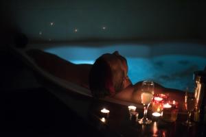 格但斯克Grey Secret Champagne Apartament Spa的阴暗的女人躺在浴缸里,蜡烛