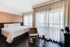圣保罗Radisson São Paulo Paulista的酒店的客房 - 带一张床、椅子和窗户
