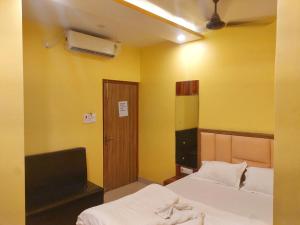 ForbesganjHotel Shobha Forbesganj的一间卧室设有两张床、一台电视和黄色的墙壁。