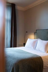 希佛萨姆多朋伯格别墅酒店的一间卧室配有一张带白色床单的床和一扇窗户。