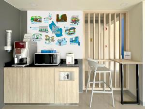 北碧Hop Inn Kanchanaburi Building A的厨房配有带微波炉的柜台和桌子。