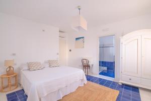 维耶斯泰朱利亚公寓的白色卧室配有床,铺有蓝色瓷砖地板。