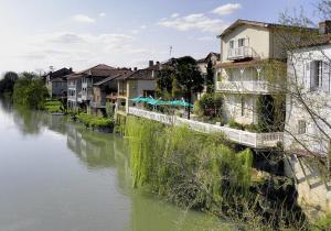 Grenade-sur-lʼAdourStudio de Tourisme Tilleuls的河里乡间小溪,河里边有房屋和建筑物