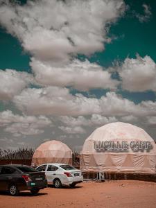 瓦迪拉姆Rum Lucille Luxury camp的两顶帐篷,汽车停在一个土场