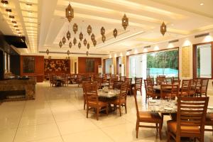克久拉霍Hotel Chandela Khajuraho的一间在房间内配有桌椅的餐厅