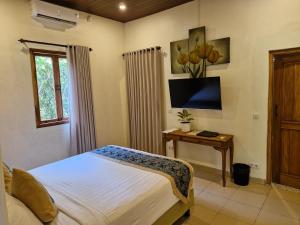 哲帕拉Jepara Garden Resort的一间卧室配有一张床和一张桌子及电视