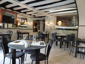 贝莱姆Logis Hôtel Restaurant L'Escale的一间带桌椅和电视的餐厅