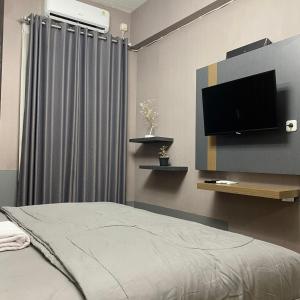 MedokansemampirApartemen Bale Hinggil Studio的一间卧室配有一张床和一台平面电视