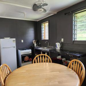 ‘OhonuaEua Accommodation的厨房配有木桌、椅子和冰箱。