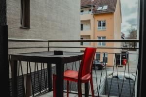 比勒费尔德3-Zimmer-Oase-Cityapartment Bielefeld Mitte 201的阳台桌子上的红色椅子