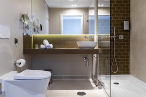 维塞乌Avenida Boutique Hotel的浴室配有卫生间、两个盥洗盆和淋浴。