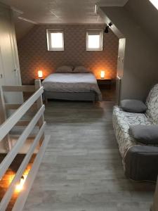 康布雷MAISON AVEC JACUZZI PRIVATIF的一间卧室配有一张床、一张沙发和两个窗户。