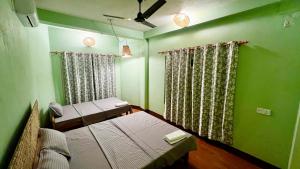 巴拉特布尔Paris Guest House Airport的一间设有两张床和绿色墙壁的客房