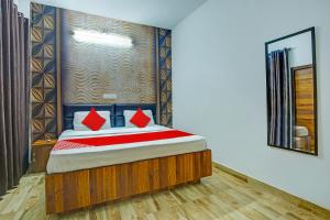 卢迪亚纳OYO HOTEL WINNER INN的一间卧室配有一张带红色枕头和镜子的床