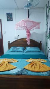 亭可马里KANTHI GUEST INN的一张带粉红色遮阳伞和毛巾的床
