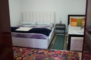 KukësSuperPanorama GuestHouse的卧室配有白色的床和色彩缤纷的地毯。