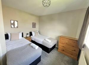 克劳利Contractors welcome 3 bed house with parking by Eagle Owl Stays的一间带两张床和木制梳妆台的卧室