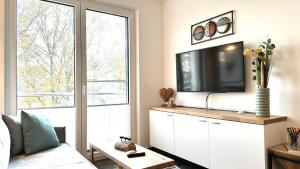 ZirchowApartment "Sonnendeck" - Haffresidenz的客厅配有白色橱柜上的平面电视