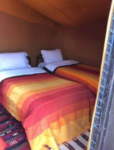 梅尔祖卡Desert Berber Camp的两张睡床彼此相邻,位于一个房间里