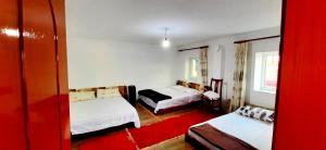 KukësSuperPanorama GuestHouse的酒店客房带两张床和红色地毯