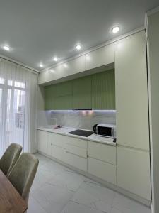 阿斯塔纳Нурсултан-сити的厨房配有白色的柜台和绿色的橱柜