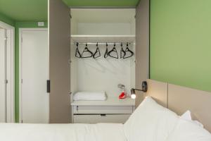 库里提巴Easy Life Campus PUC by Xtay的一间卧室配有一张床和一个带衣架的衣柜