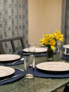乔奥诺奥尔Sunset Villa的一张桌子,上面有盘子和玻璃杯,花瓶上还有黄色的花