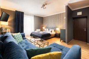 瓦尔季采Wine & Wellness hotel Besední dům的客厅配有蓝色的沙发和床。