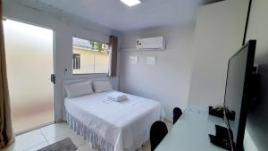 JaguariaívaFlat 01的一间小卧室,配有白色的床和窗户
