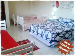 瓜拉派瑞Suítes de Setiba - HOSPEDARIA OCA RUCA的一间卧室配有两张单人床和一把椅子