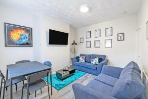 利物浦Air Host and Stay - Scott House, 3 bedroom house sleeps 7 free parking的客厅配有蓝色的沙发和桌子