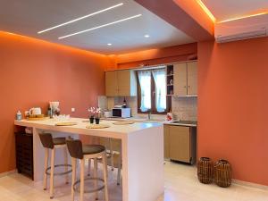 阿菲托斯Cynthia - Christine's House的厨房设有橙色墙壁和带酒吧凳的白色岛屿