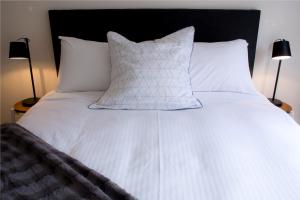 墨尔本墨尔本唐人客栈的一张带白色床单和枕头的床以及两盏灯