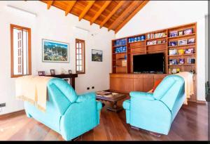 科蒂亚Casa na Granja Viana - Cotia的客厅配有2把蓝色椅子和电视