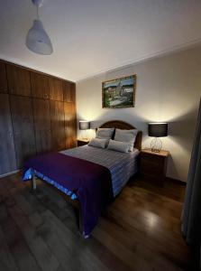 雷森迪Casa do eirô的一间卧室配有一张大床,提供紫色床单和枕头