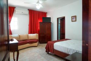 El Catey努埃沃阿玛妮赛酒店的一间卧室配有床、沙发和红色窗帘