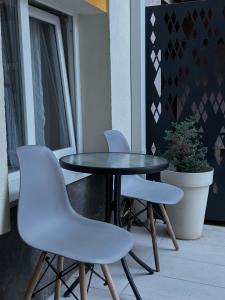 尼什Vila Storia的阳台上配有一张黑桌和两把白色椅子