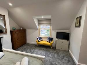 梅尔顿莫布雷The Loft at Scalford House的一间卧室配有黄色的沙发和一台电视