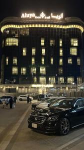 吉达ِAluya Hotel的夜间停在大楼前的汽车