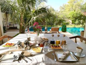 恩加帕鲁Villa YEMAYA - Villa d'hôtes的一张带食物的白色桌子和游泳池
