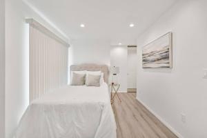 洛杉矶Modern 1-Bedroom Home in a Prime LA Location的白色卧室配有白色的床和绘画作品