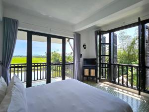 Hiếu NhơnÉn Garden Resort Hoian的一间卧室配有一张床,阳台配有窗户