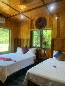和平Quế Homestay的配有木墙和窗户的客房内的两张床