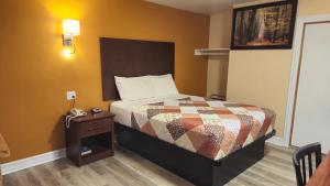 Deep River迪普里弗汽车旅馆的一间卧室配有一张床和一张桌子及电话